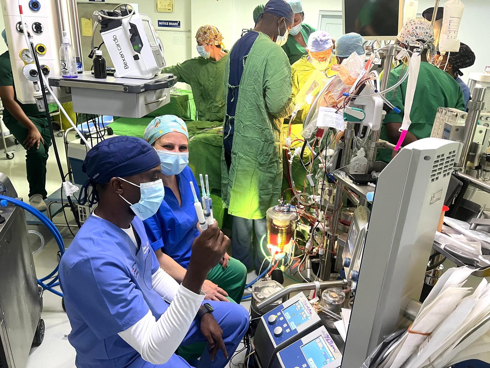 A perfusionist operates the heart-lung machine while a surgical team works in a cardiac operating theatre