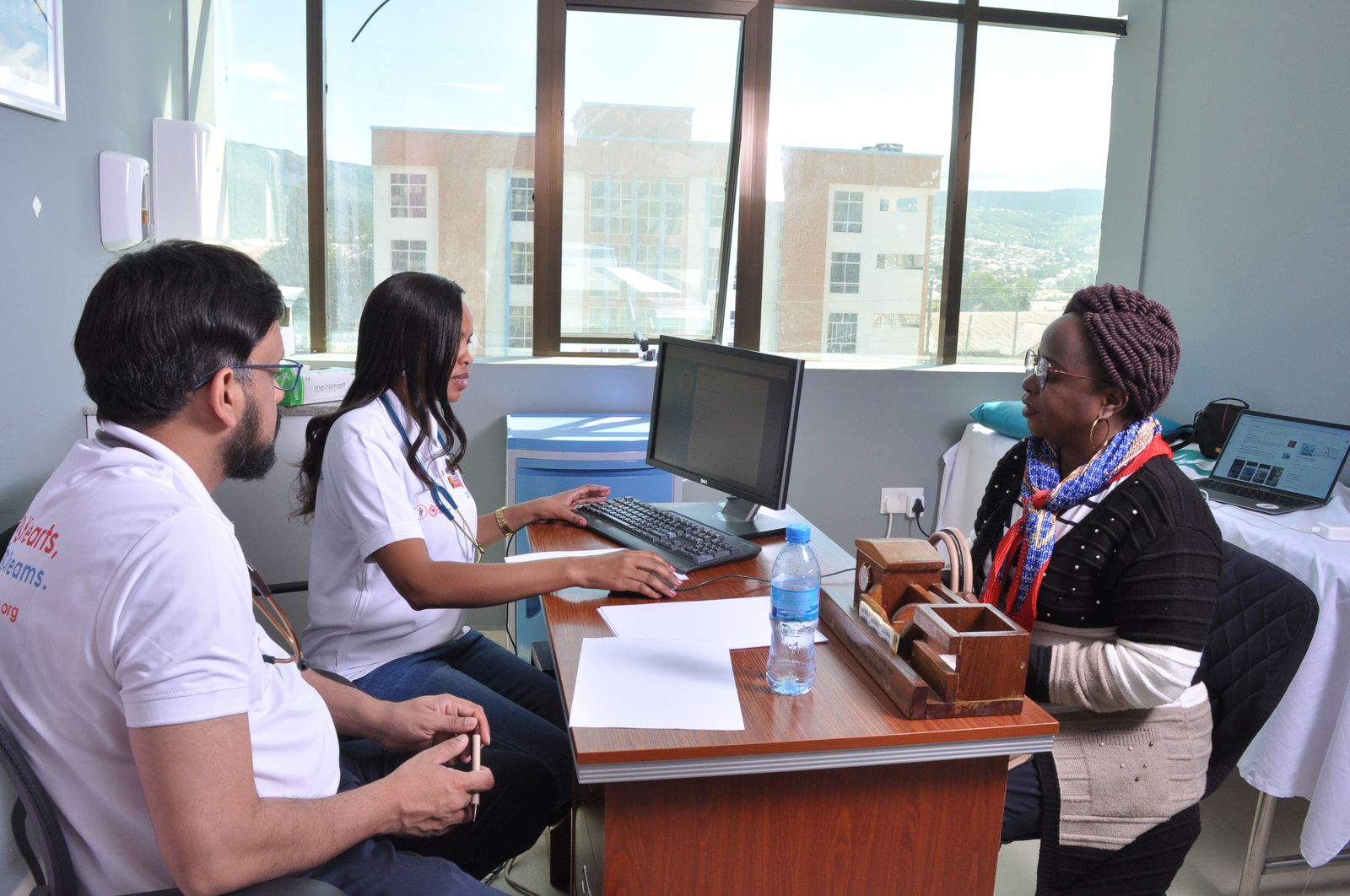 A clinician consults with a family at a desk during a screening programme