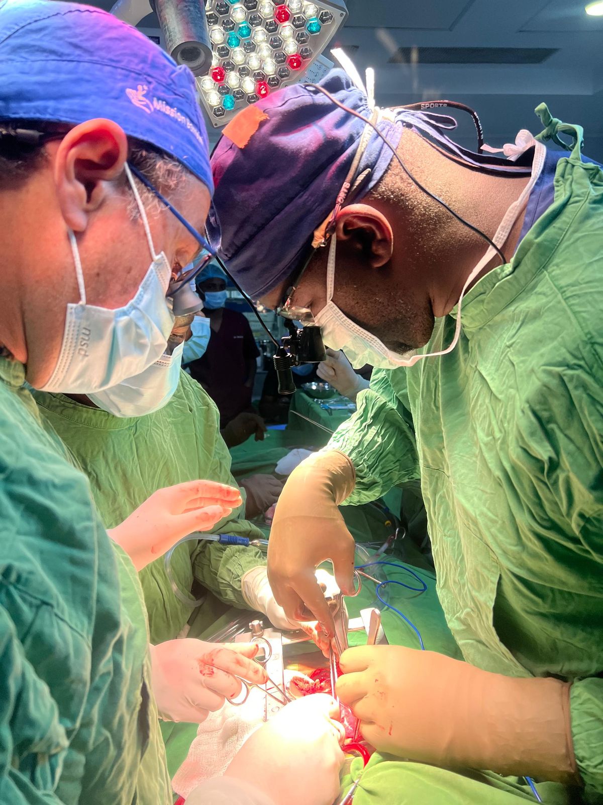 Two clinicians examine a small child with a handheld ultrasound probe at the bedside