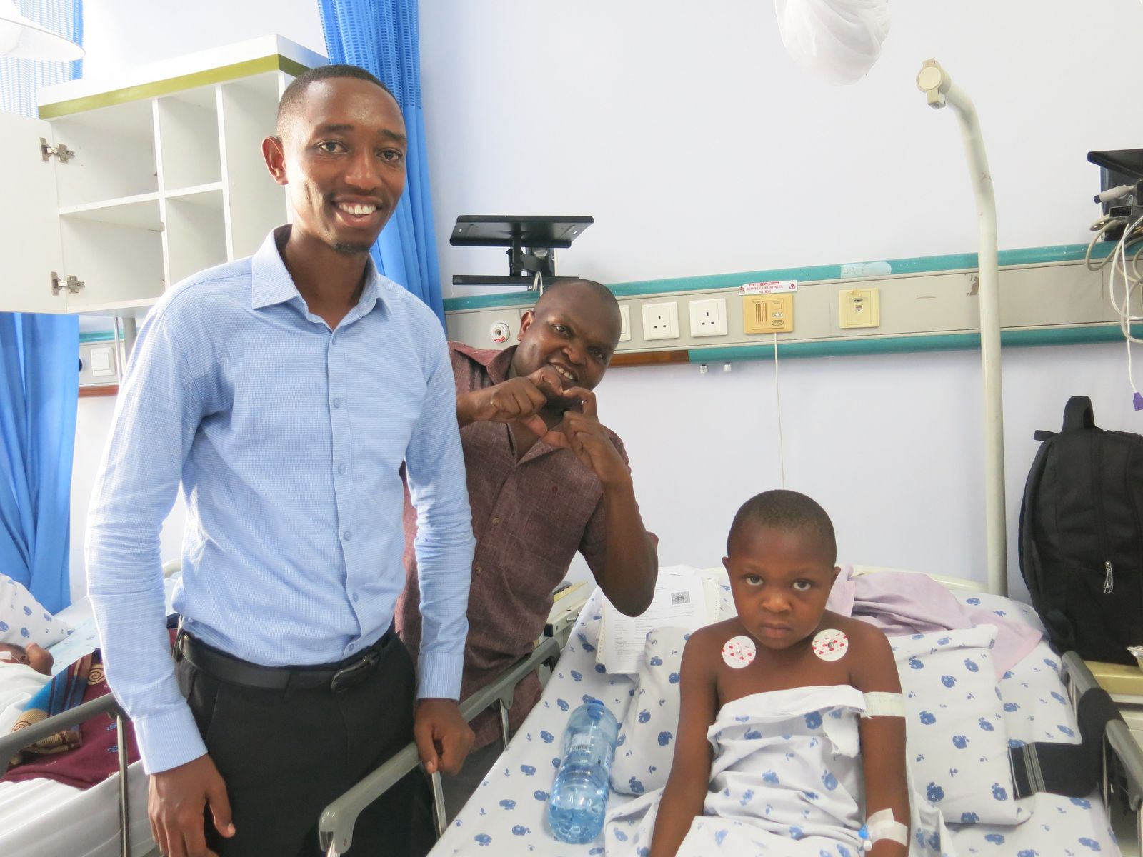 A One New Heart Tanzania team member visits a child recovering in a hospital bed