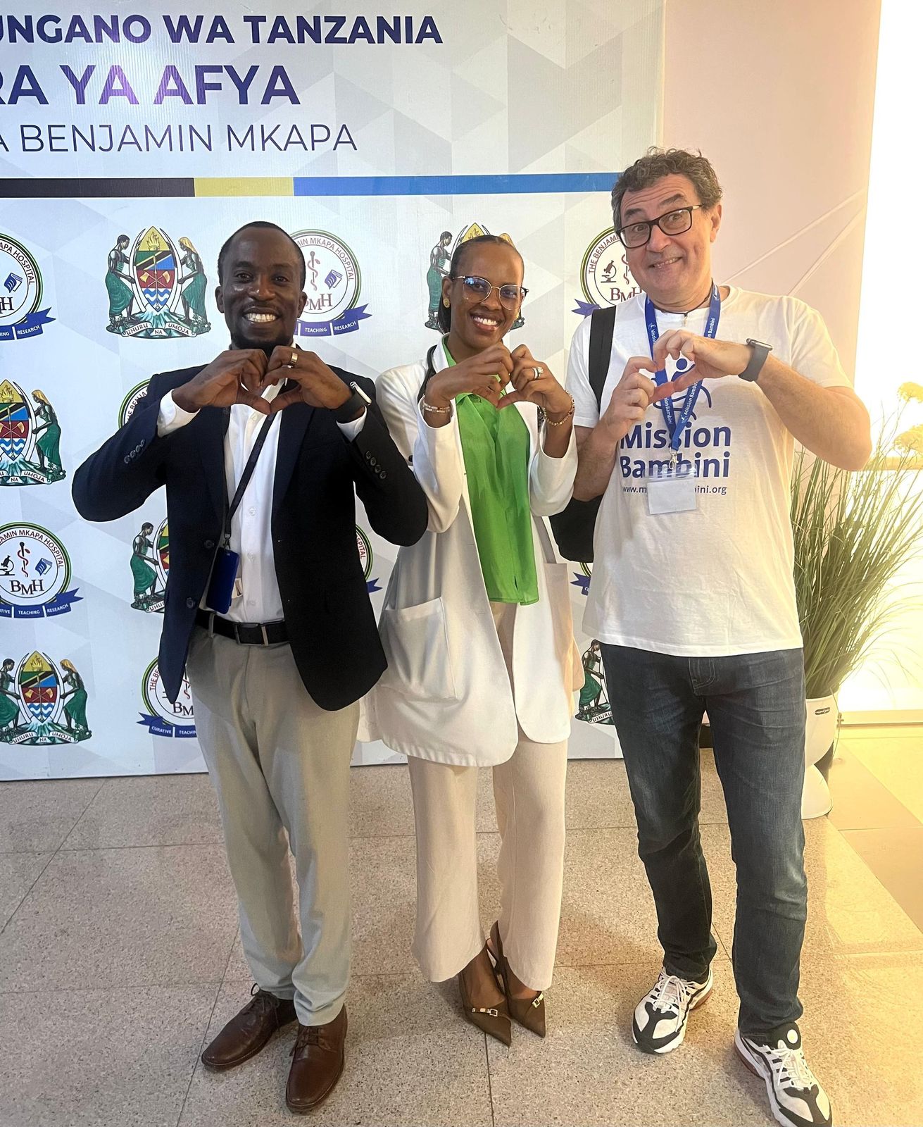 Team members and a Mission Bambini surgeon make heart signs at Benjamin Mkapa Hospital