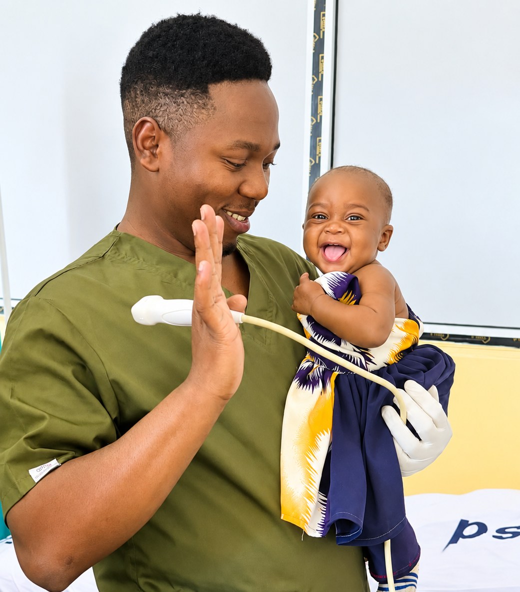 A clinician holding an ultrasound probe raises his hand to a laughing baby