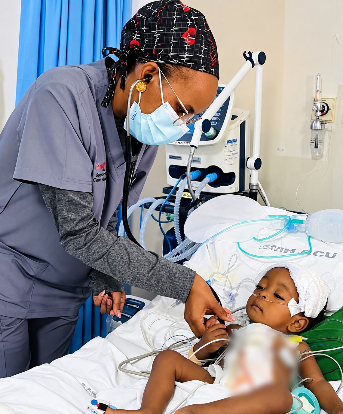 A clinician checks on a young child recovering in intensive care