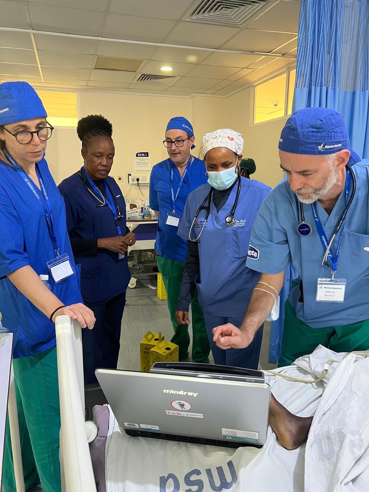 Clinicians gather around a monitor during a training session